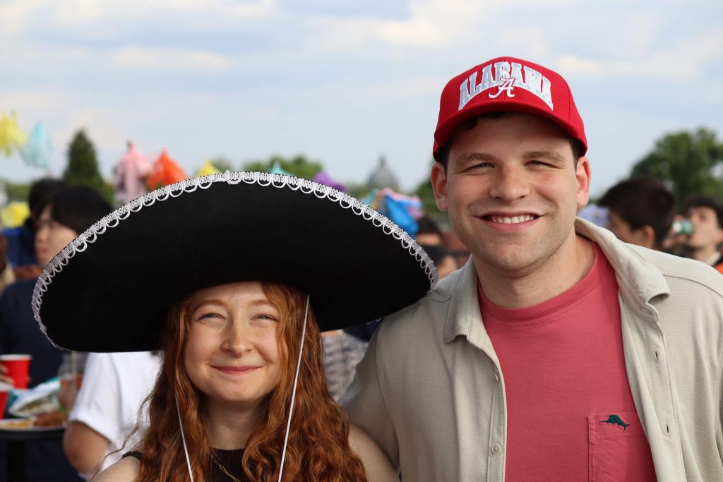 John Richardson stands on the right with a University of Alabama hat next to a woman on the left in a large sombrero hat.